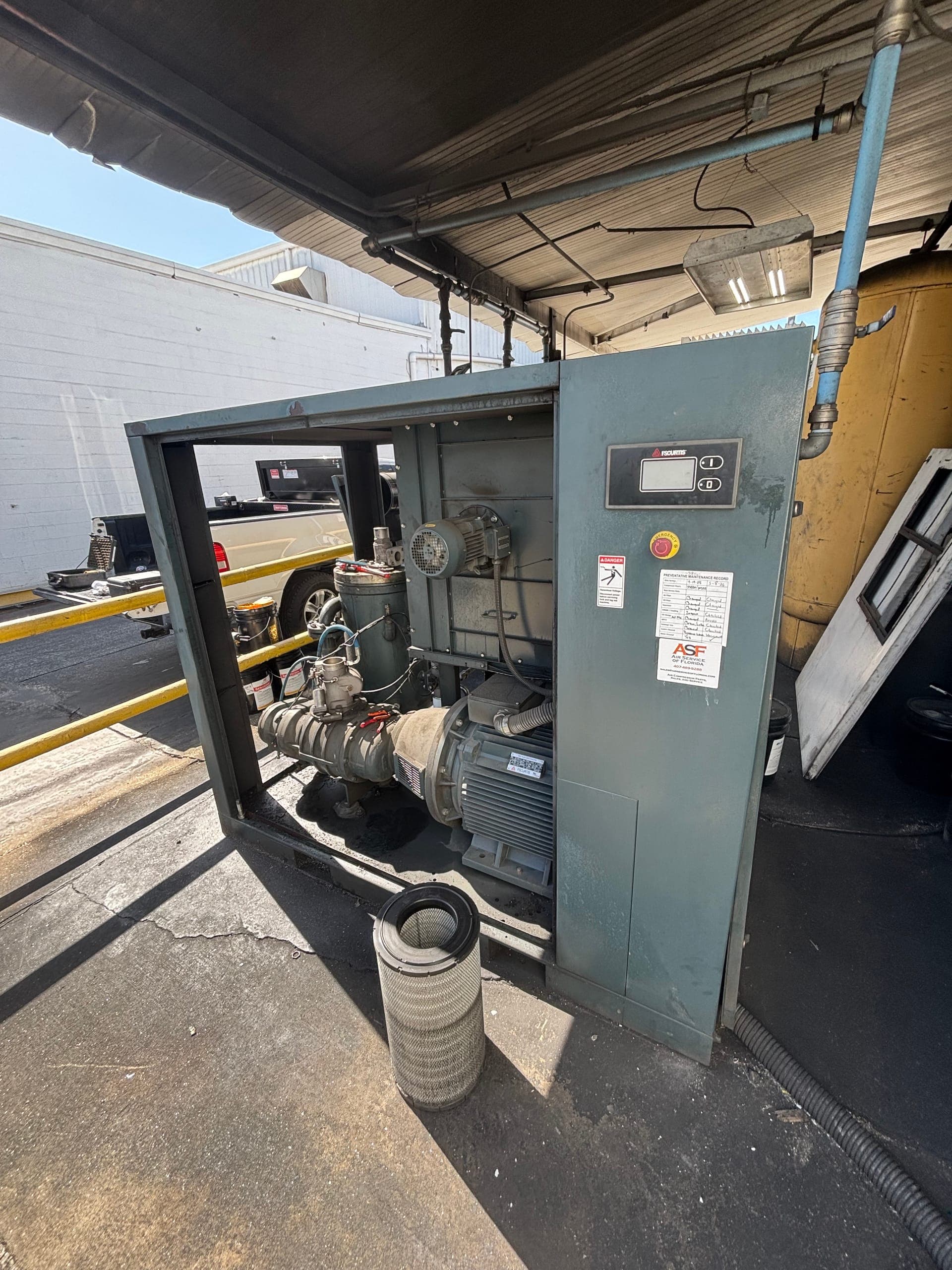technician performing preventive maintenance on an industrial air compressor